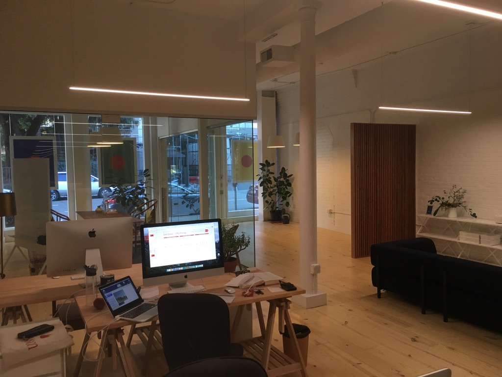 The Punch San Francisco storefront studio — trestle desks, white brick, and the street through the glass
